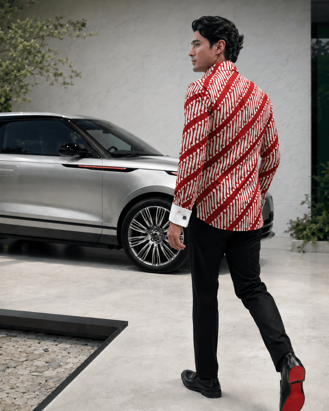 Concept image from behind of a man walking in a red-and-white diagonal-patterned shirt with white cuffs.